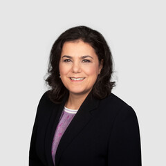 Prof. Aprea has shoulder-length dark hair and wears a dark blazer and a purple blouse.