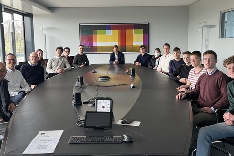 People sit around a black table with electronics on it.