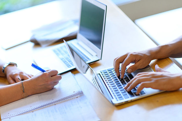 Hände, Laptops und Block auf Tisch