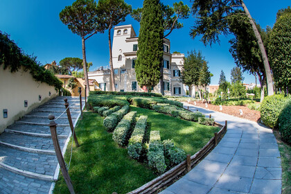 Gartenanlage mit Grünfläche und Wegen und Gebäude im Hintergrund