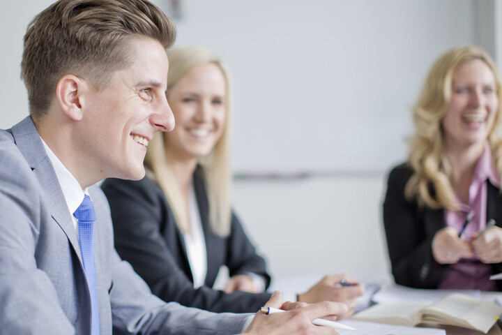Lachende Personen sitzen um Tisch