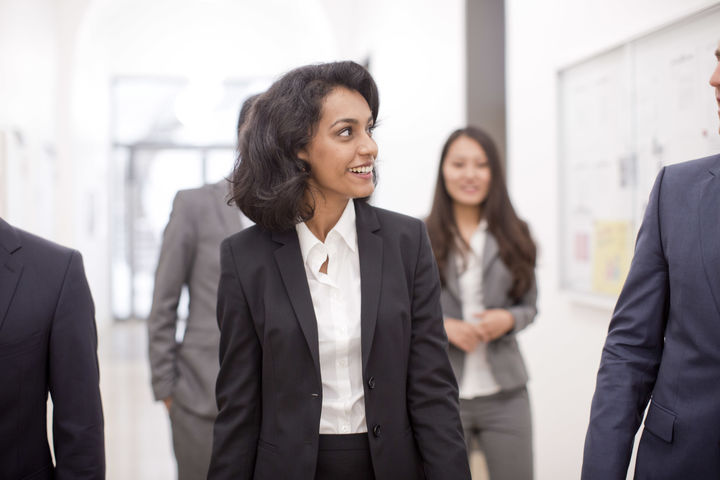 Personen in Business Kleidung laufen den Flur entlang