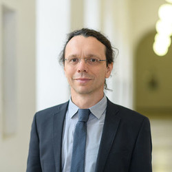 Prof. Ifenthaler has dark hair and glasses and wears a suit and tie.